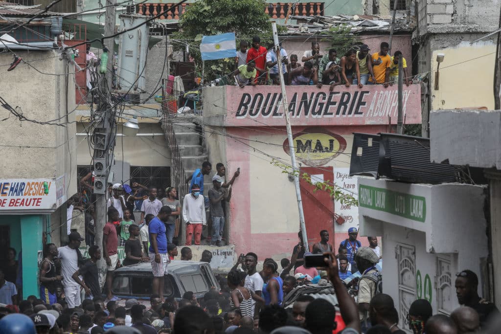 Una multitud de personas rodea al coche de Policía 
<b>que transporta a dos hombres armados</b> 
<b>arrestados </b>en el suburbio de Petionville en Puerto Príncipe tras el asesinato del presidente.