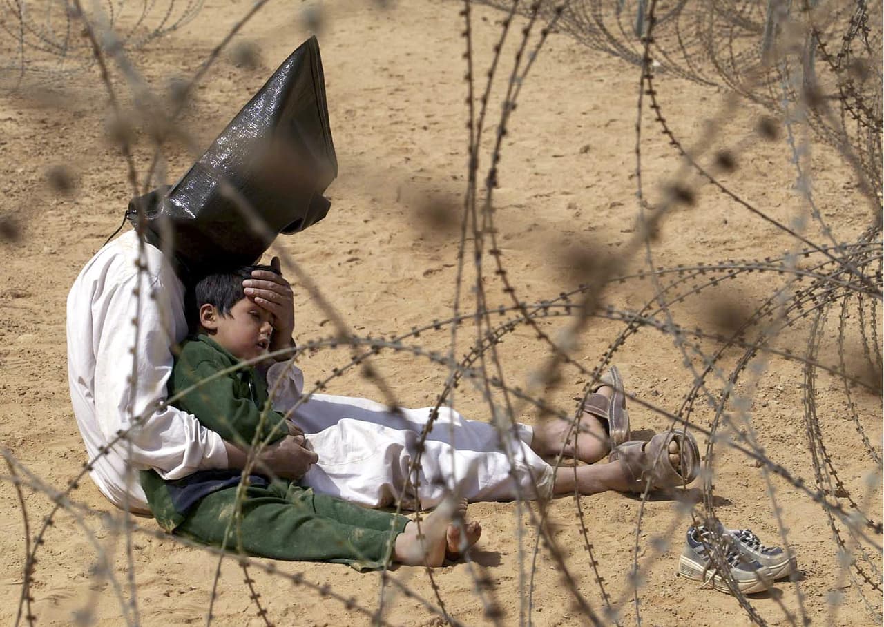 Otra imagen conmovedora de una guerra es esta de 
<b>un prisionero de guerra iraquí consolando a su hijo</b> de 4 años en un centro de reagrupamiento en Afganistán, el 31 de marzo de 2003. El Ejército estadounidense no quiso separar al padre y al hijo.