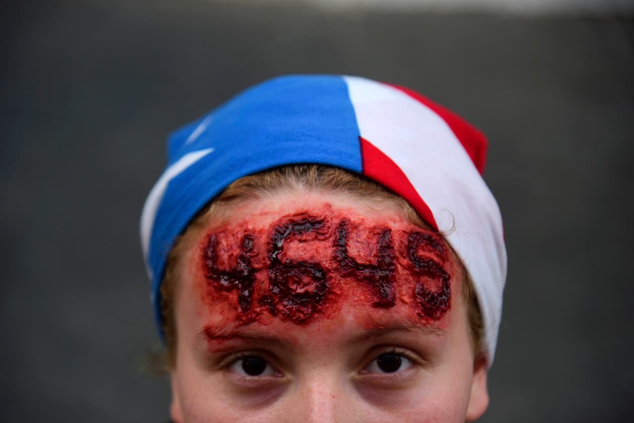 Por otro lado, las dimisiones en la administración de Rosselló continúan y el presidente del Banco de Desarrollo Económico (BDE) de Puerto Rico y director ejecutivo de la Autoridad de Financiamiento a la Vivienda (AFV), Gerardo Portela, presentó su renuncia a los dos cargos. En la foto, una joven lleva el número de muertes que se atribuyen al huracán María.