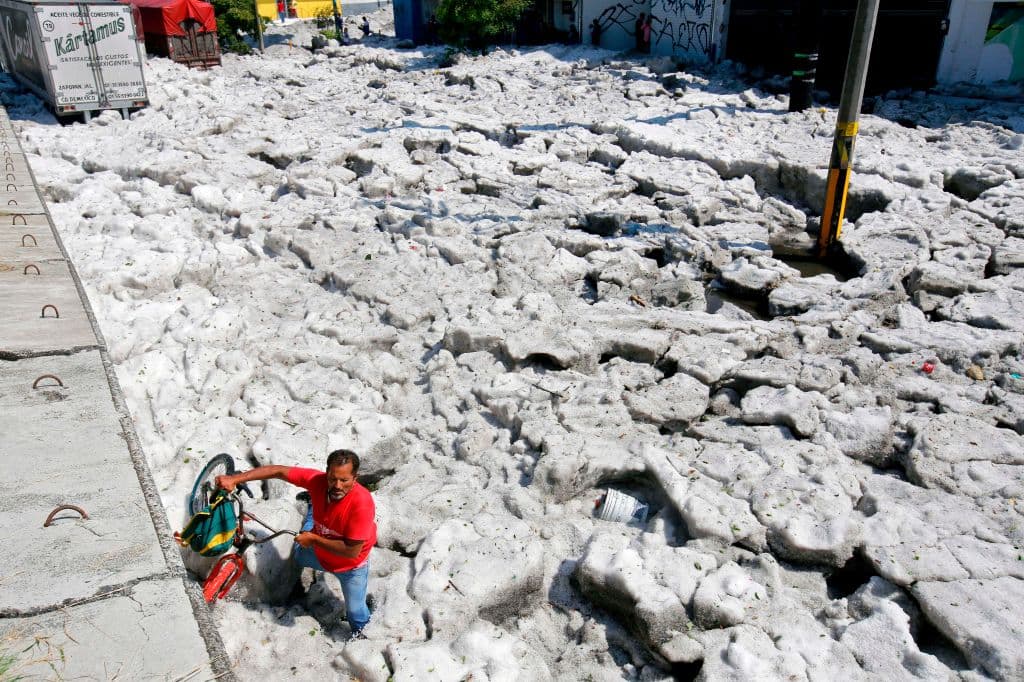 Un hombre acarrea su bicileta entre el granizo en Guadalajara, Jalisco, este domingo 30 de julio.