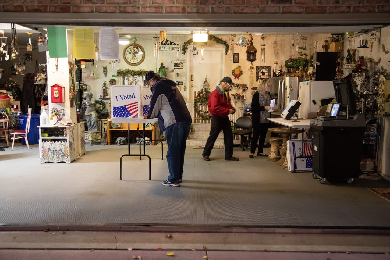 Bob Henrich (izq.), coordinador de votaciones del condado de Allegheny, inspecciona la configuración del lugar de votación en un garaje de residentes privados en Pittsburgh, Pensilvania, para las elecciones de mitad de período de EE. UU. el 8 de noviembre de 2022.
