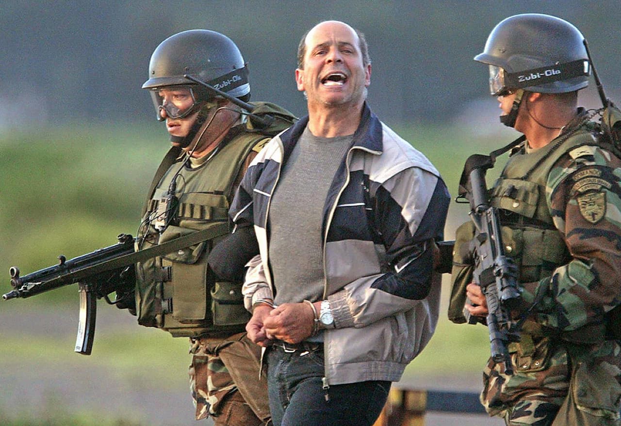 <b>Extradición y cárcel para guerrilleros notables. </b>También en esa época fueron capturados alias Simón Trinidad, líder y negociador del grupo y Martín Sombra, el llamado carcelero de las Farc, quien fue recluido en la cárcel Modelo de Bogotá donde todavía permanece detenido. En la foto, tomada en enero de 2004, Trinidad gritó vivas a la guerrilla mientras era trasladado antes de ser extraditado a Estados Unidos.