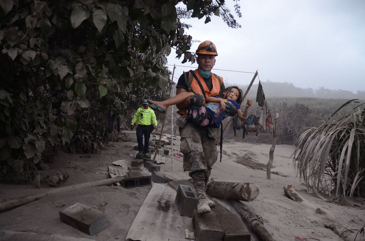 A rescue worker with a child in El Rodeo, Escuintla, on the slpes of the Fuego volcano in Guatemala.